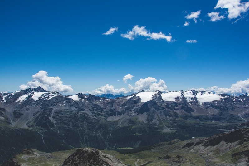snow capped mountains under a blue sky with scattered clouds, snow blanket on a mountain ridge 4k