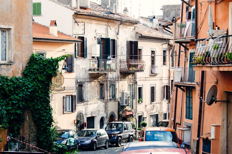 street view of a poor urban setting with run down cars parked on the street next to older houses, poor urban neighborhood 4k