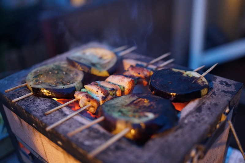 charred meat and vegetables on skewers over a coal filled grill outside, bbq skewers 4k