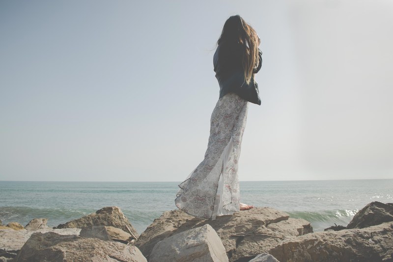 woman in a dress standing on a rock at the valencia coastline, woman in a dress 4k