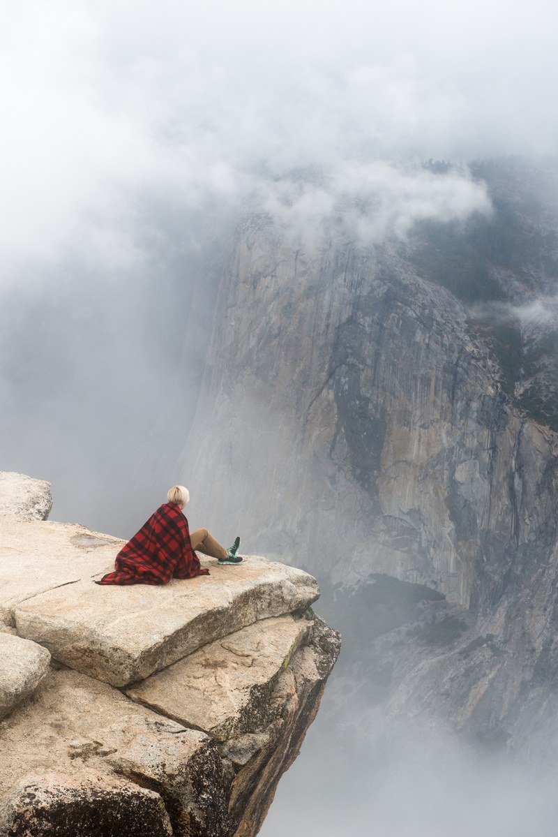 hiker sits on the rocky ledge of a high mountain in yosemite national park, fearless climbs 4k