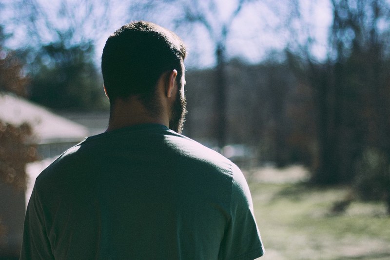 a man wearing a green shirt with his back to the camera, behind a man 4k