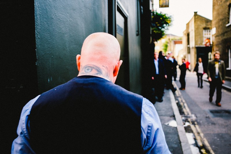 bald man with a tattoo walks down a busy narrow street in waterloo, walking through waterloo 4k