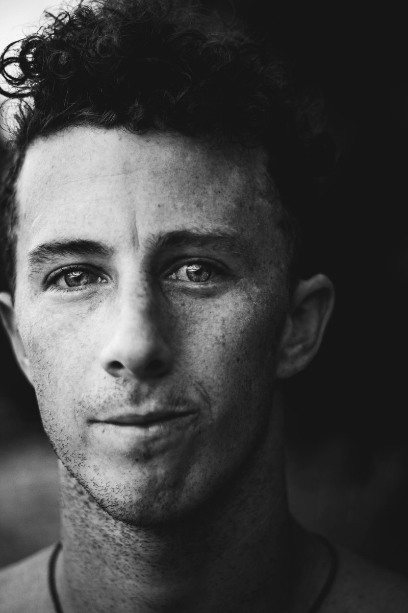black and white close up shot of dark haired young man with freckles and curly hair, curly hair and freckles man 4k