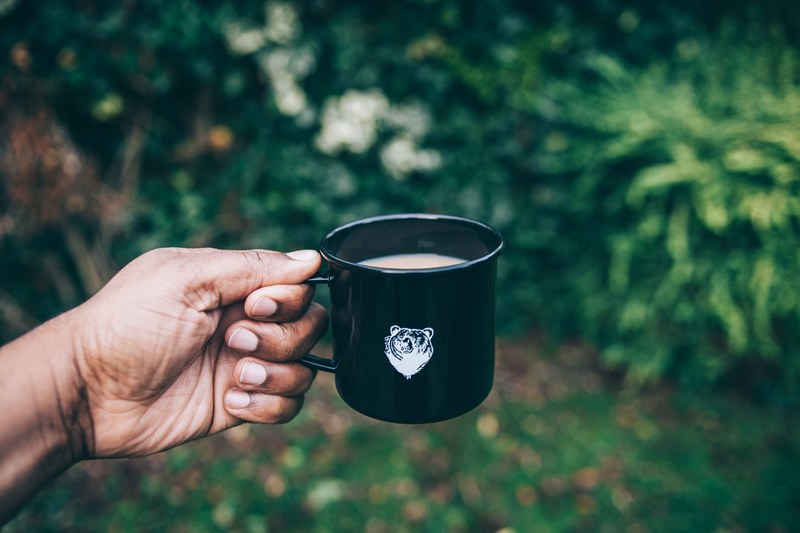 a person holding a black mug with a bear on it, tea in a mug 4k