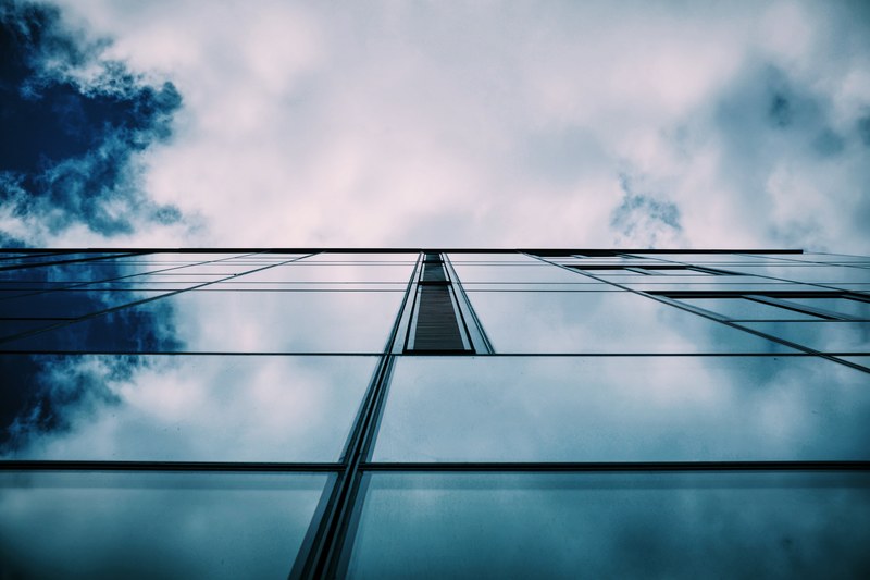 a low angle shot of the glass facade of a tall building, tall mirror like facade 4k