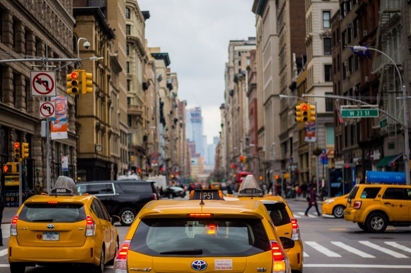 taxi cabs stop at a red light at a busy intersection in downtown manhattan, yellow cabs in nyc 4k