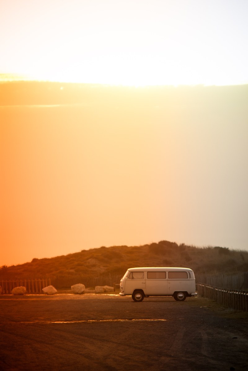 vintage vw van parked on the side of the desert road, golden hour road trips 4k