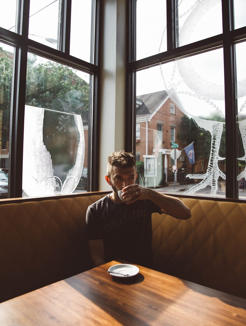 a man drinking coffee in the corner of a coffee shop in cincinnati, cincinnati coffee shop corner 4k