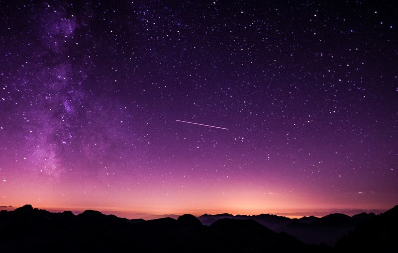 a starry purple hued night sky over the silhouettes of undulating mountains, sublime purple night sky 4k