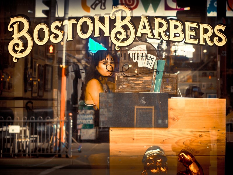 a woman seen through the barbershop window, barbershop storefront 4k