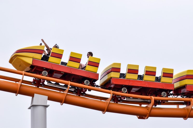 three people sitting on an empty roller coaster excited in a santa monica amusement park, pacific park santa monica 4k