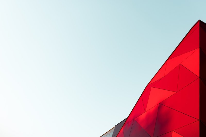 a light blue sky with a bright red triangular top of a building just visible, red geometric building 4k