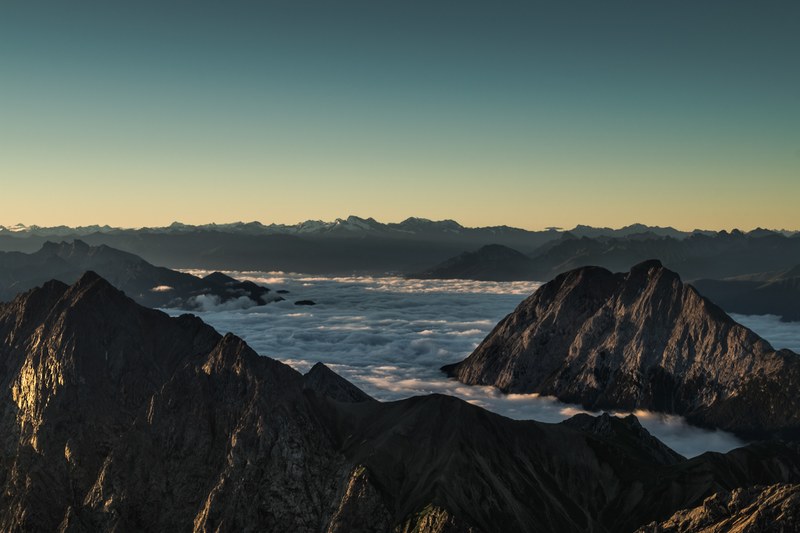 craggy mountains rising up above clouds during sunrise, cloudy sunrise in the mountains 4k