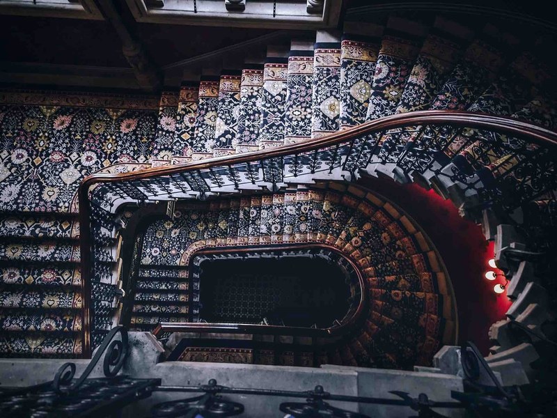 a spiral staircase with ornate carpet and banister designs, fancy spiral staircase 4k