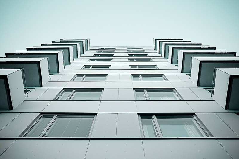 looking up at gray high rise apartment with balconies and square windows, high rise building from below 4k