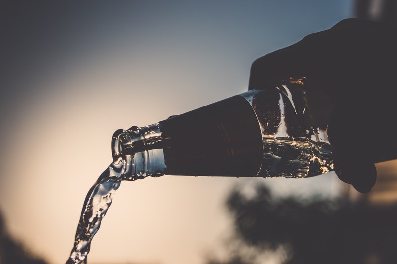 a person pouring out a bottle of water in an old glass pop bottle in sopron, emptying a glass bottle 4k