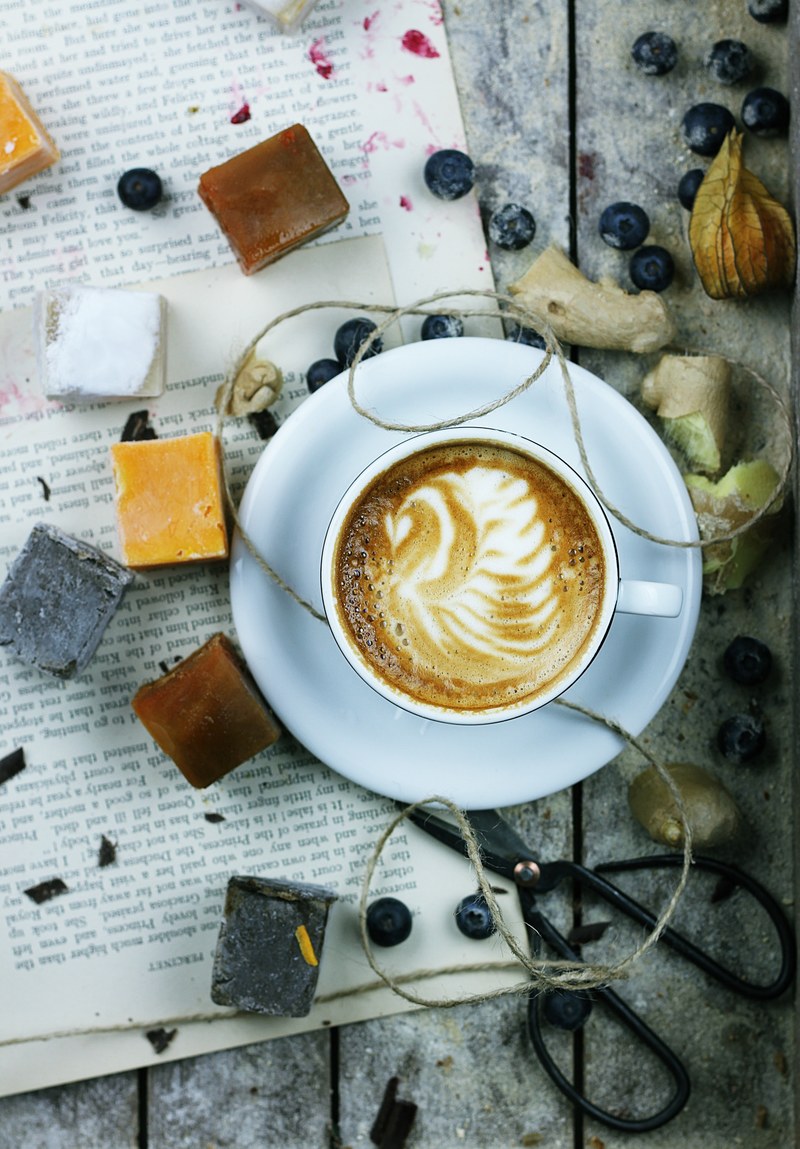an overhead shot of a cup of coffee with latte art surrounded by blueberries and various trinkets, latte art and blueberries 4k