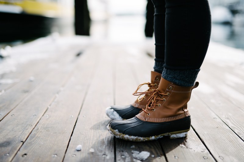 brown winter boots covered in snow are standing on a wooden floor, wearing boots on the pier 4k