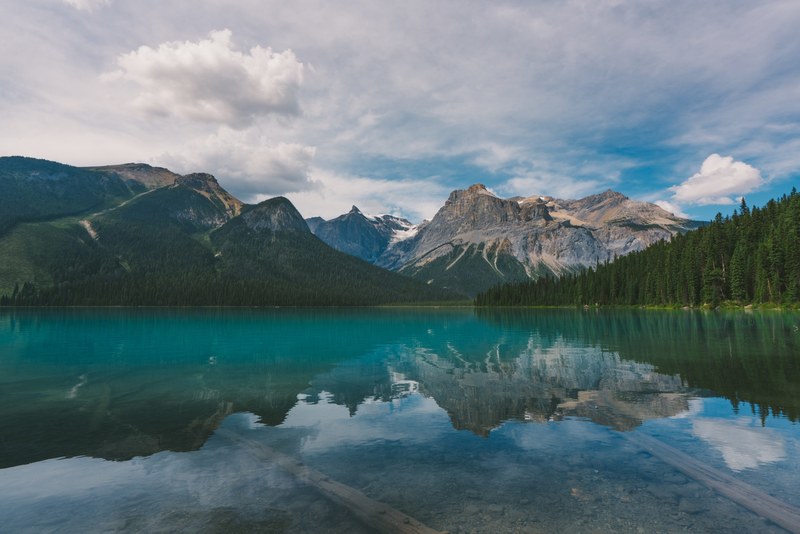 an emerald green surface of a lake near granite mountains in yoho national park, where the mountains meet the sky 4k