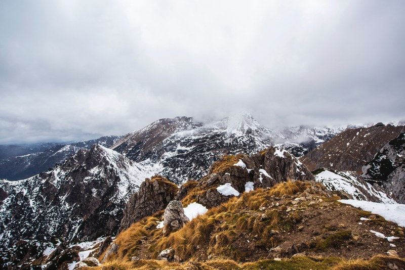 a mountainous landscape with jagged snowy ridges enveloped by thick clouds, cloudy highlands 4k