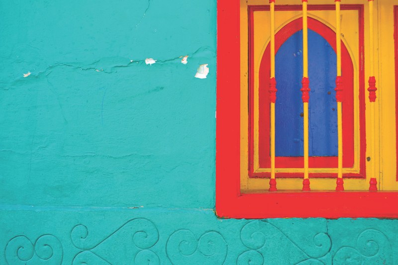 a window with its shutters painted yellow red and blue on a blue wall, colorful window shutter 4k