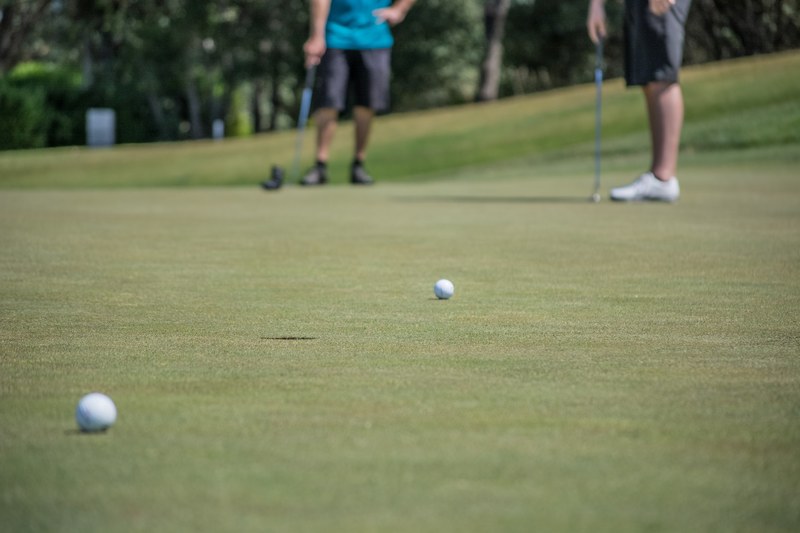two men putting to see who can score first on a golf hole, golfing against each other 4k