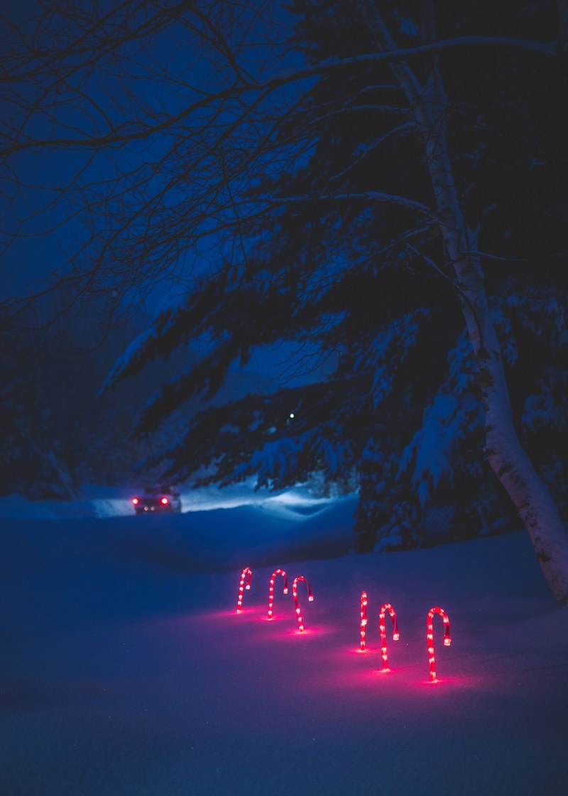 car driving away with several red glowing candy canes sticked in the snow at night, night snow winter and candy cane hd, 4k