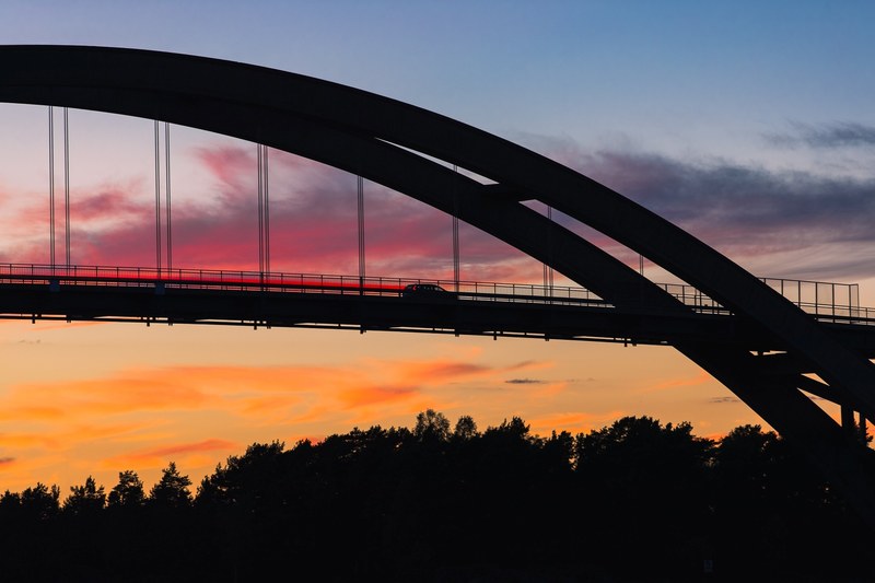 arched bridge silhouetted against a colorful sunset, silhouette of the djurbron suspension bridge 4k