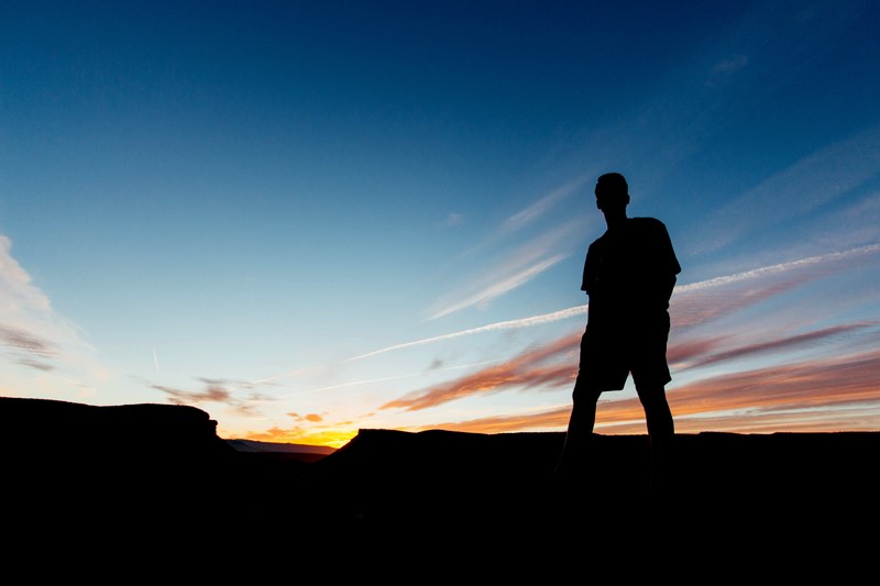 male silhouette in the late evening sunset under a mostly clear sky, sunset silhouette of man 4k