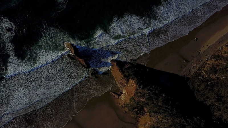 drone view of the ocean washing on a sand beach shore with rock formations at pacific city, sea washing ashore drone view 4k