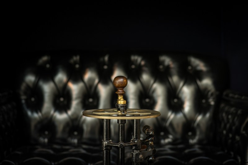 brass vintage steering wheel in front of leather couch, vintage steering wheel couch 4k