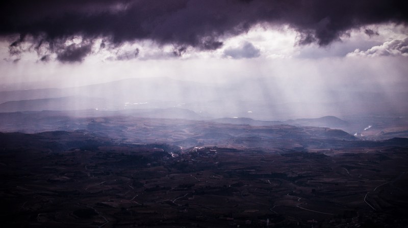 a vast rural landscape under faint light seeping in from the clouds, faint sunlight and countryside 4k
