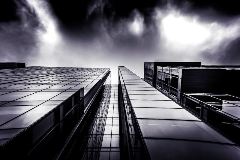 a low angle shot of a dark glass facade of an office building on a cloudy day, dark glass facade 4k