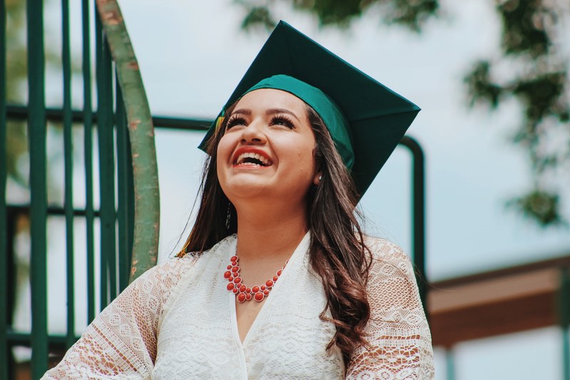 a woman wearing a graduation cap smiling and looking up at the sky, thank goodness its over 4k