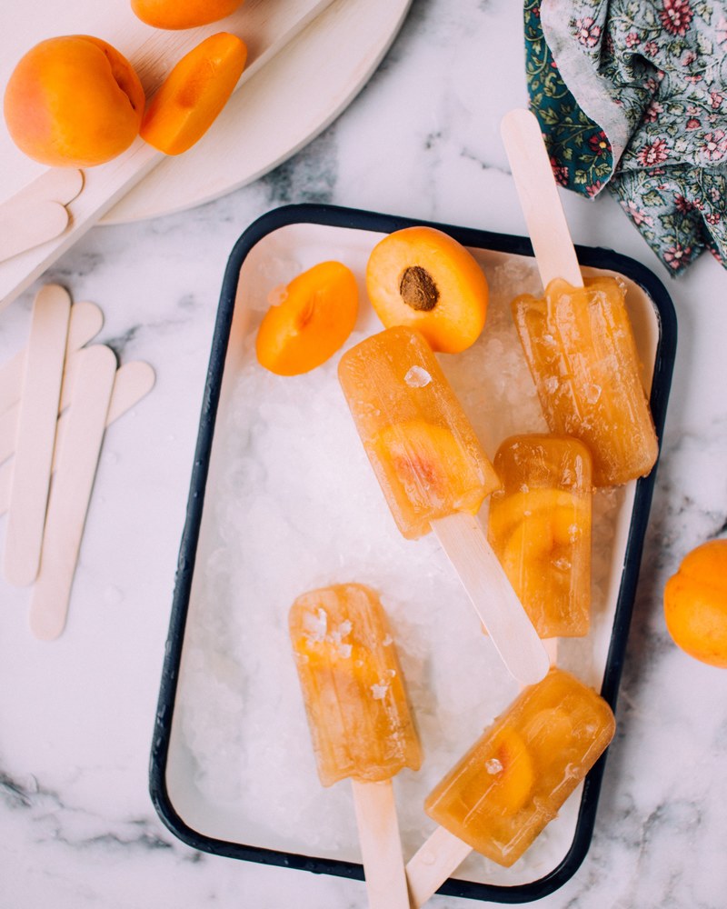 a tray with orange popsicles and pieces of apricot, apricot iced tea popsicles 4k