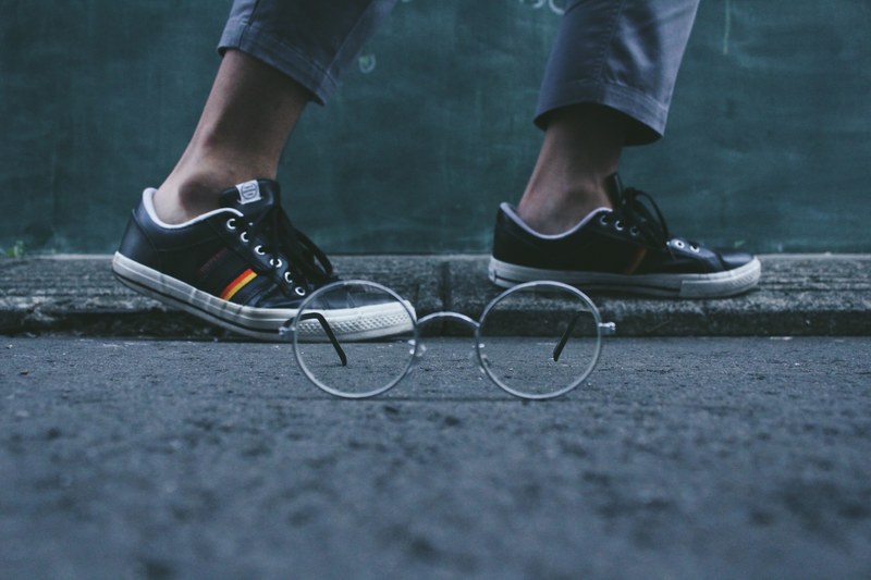 a pair of glasses on the asphalt next to a persons feet in sneakers, glasses on asphalt 4k