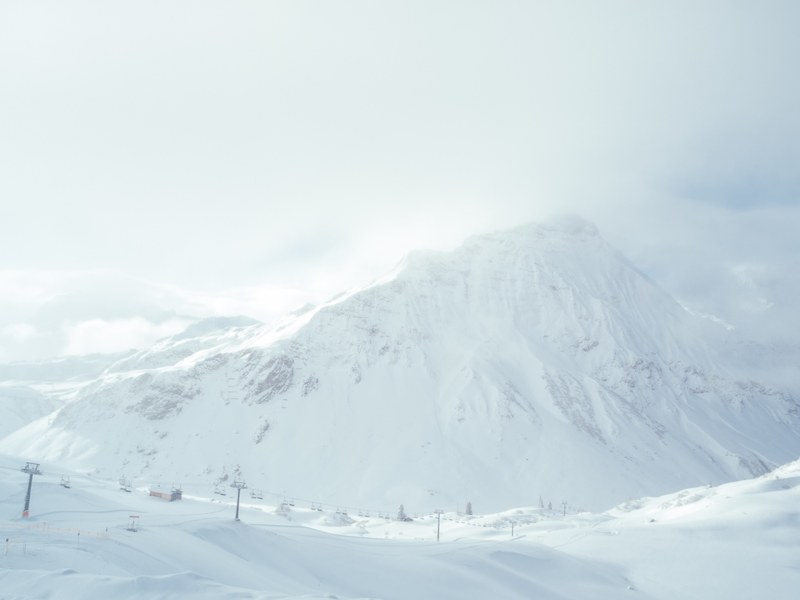 pristine snowy winter alps shrouded in fog, ski lift by a large mountain 4k