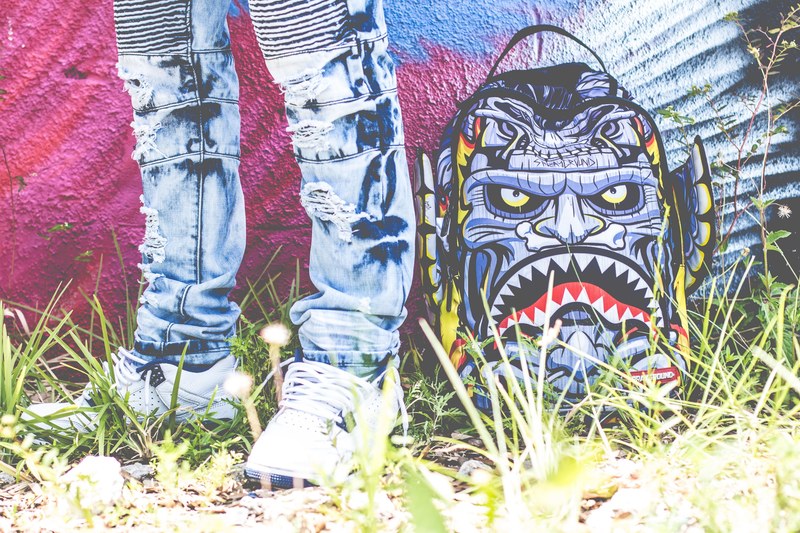 a person standing in front of a piece of graffiti art of a blue monster with sharp triangular teeth, _monster face graffiti 4k