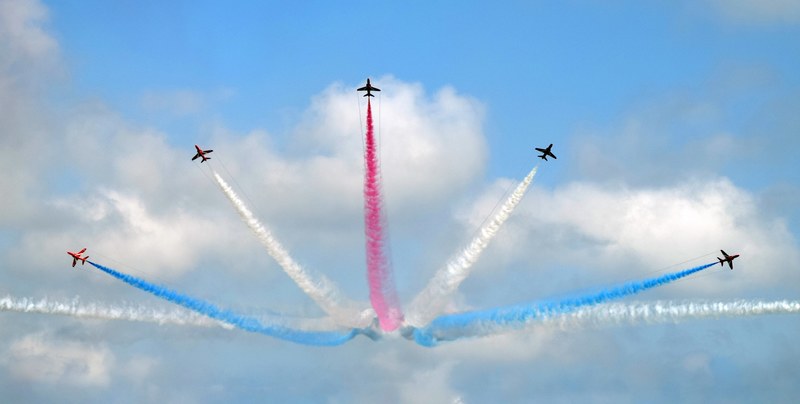 five jet planes leaving behind concentric trails in white blue and red, concentric smoke trails 4k