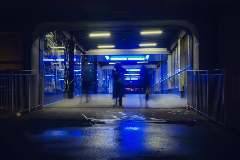 a double exposure shot with silhouettes of people an underground passage bathed in blue light, blue underground passage 4k