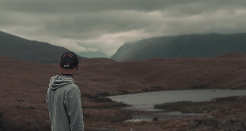 a man wearing a hat and a hoodie standing in front of lake alexandrina in a cloudy weather, man standing by lake 4k