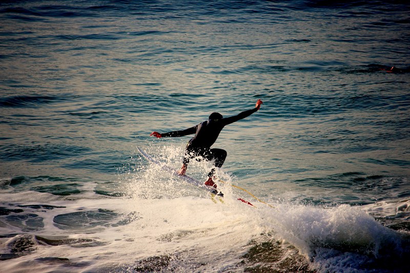 a surfer wearing a wetsuit arms outstretched in the sea at biarritz, stretching surfer 4k