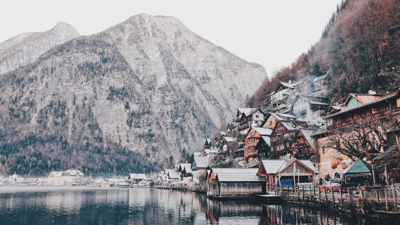 a picturesque village on the side of a wooded mountain by a lake, quaint mountain village over a lake 4k
