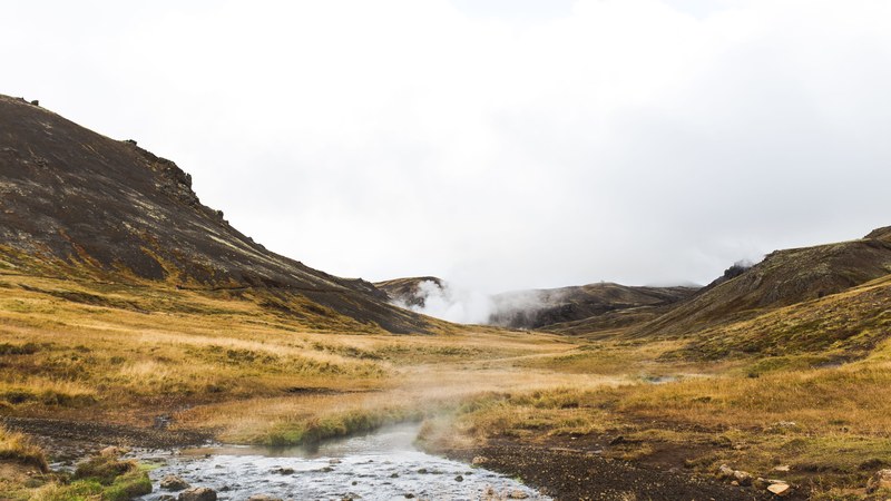 steam rising up above a cold grassy field surrounded by rocky hills in iceland, steam over an icelandic field 4k