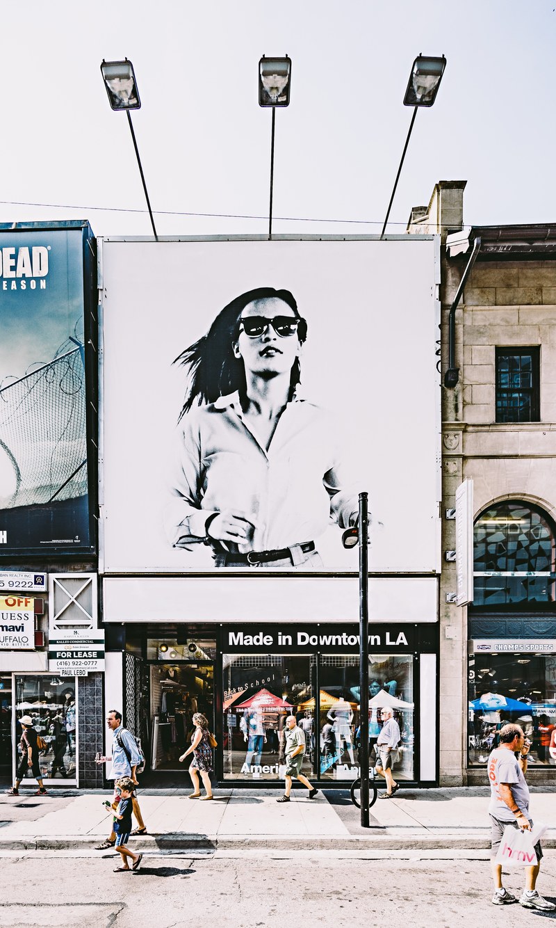 a large advertisement with an elegant woman in sunglasses over a storefront, storefront with a billboard 4k