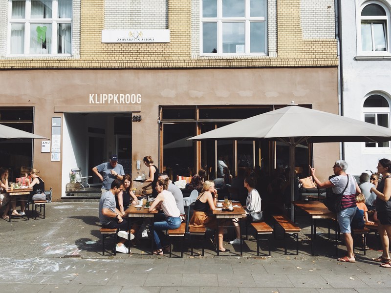 people talking over coffee while seated in front of a coffee shop, coffee shop entrance 4k