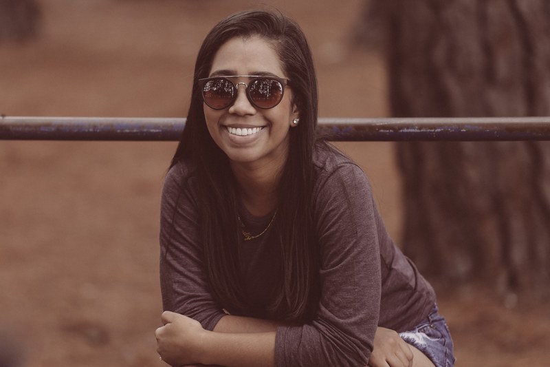 woman in sunglasses smiles in front of a railing in parque da cidade, woman in parque da cidade 4k