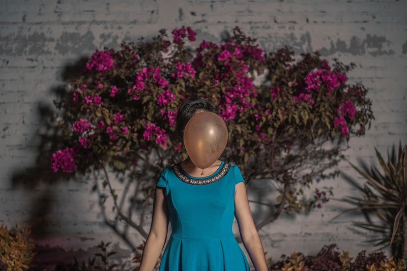 a woman in front of a flowering tree with her face covered by a balloon, women in the air 4k
