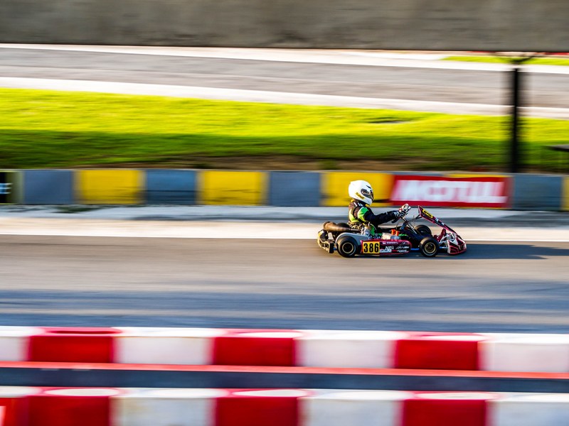 a blurry shot of a person driving a go kart on race track, go kart on a race track 4k